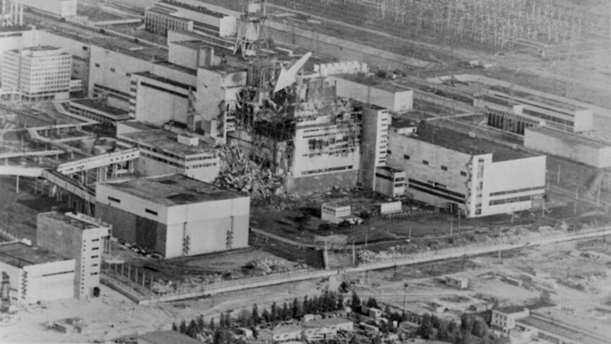 Celkový pohled na Černobylskou jadernou elektrárnu krátce po výbuchu jednoho z reaktorů (šipka označuje místo havárie)