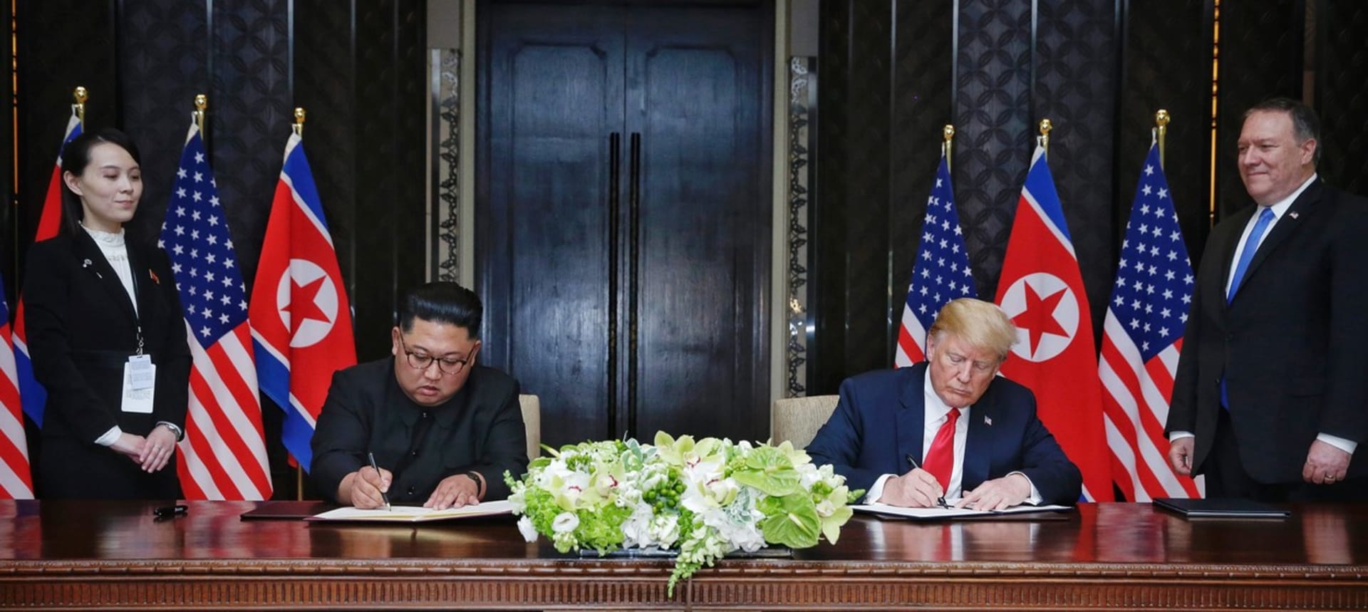 Summit Kim Čong-una a Donalda Trumpa v červnu 2018. Kim Jo-čong a ministr zahraničních věcí USA Mike Pompeo přihlížejí podpisu dohody mezi státníky.