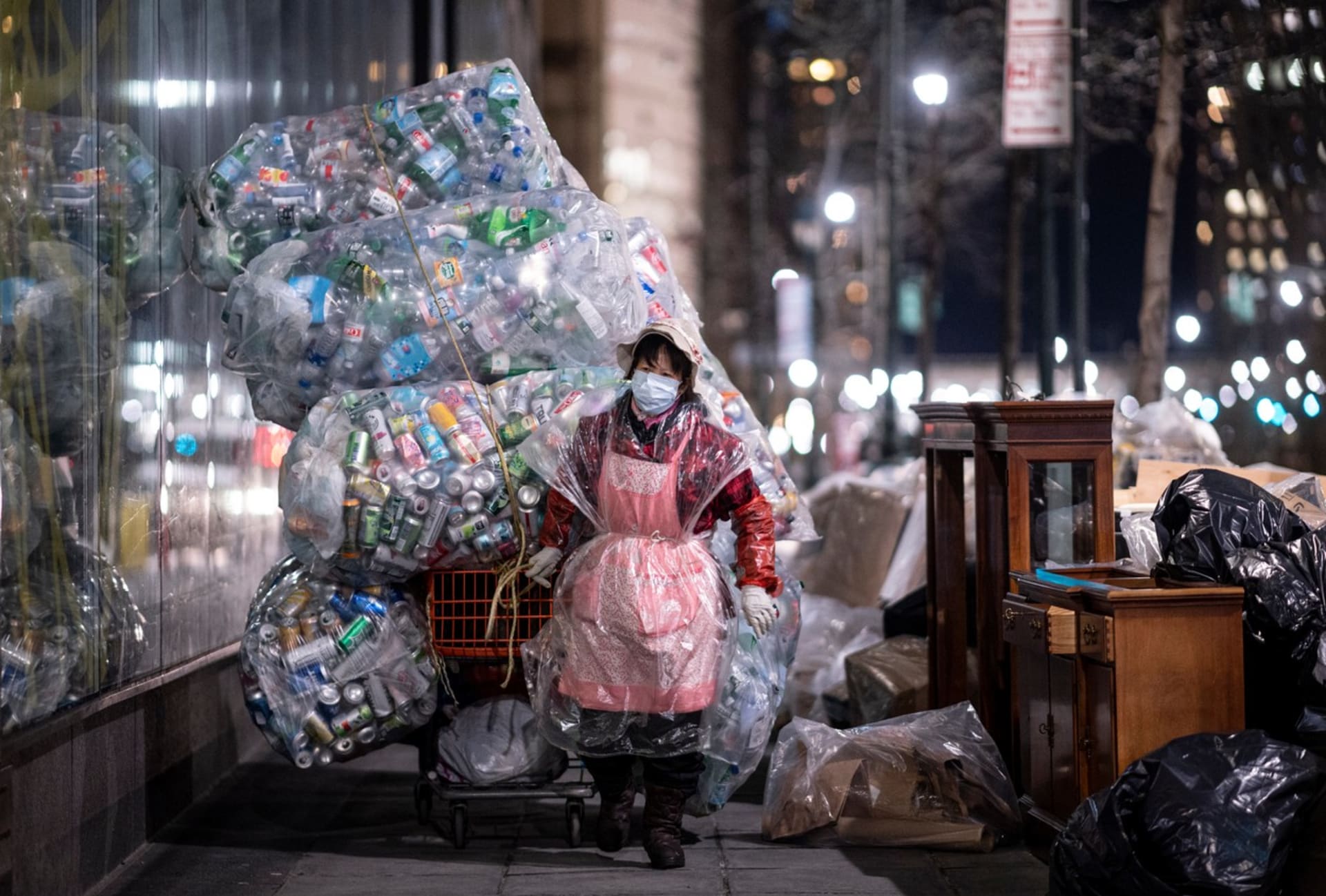 Žena vláčí ulicemi New Yorku obří pytle s plastovým odpadem.