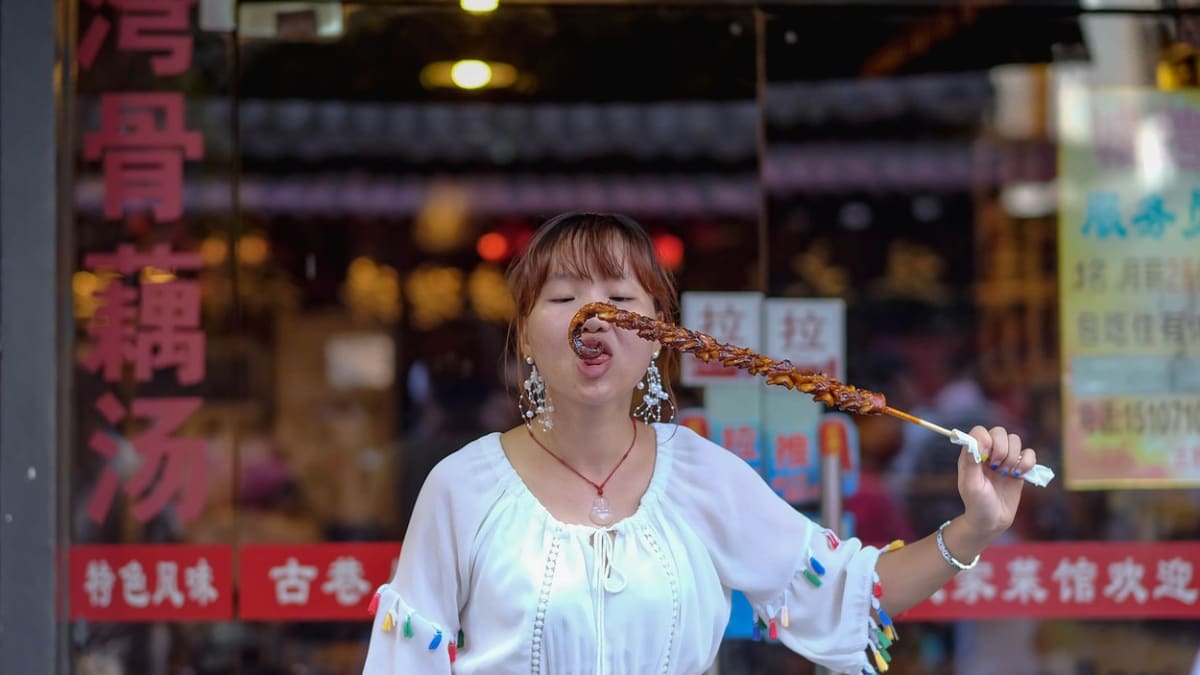 Žena pojídá grilované krevety na trhu v čínském Wu-chanu.