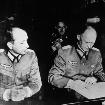 7.května 1945 v americkém hlavním stanu v Remeši byl podepsán předběžný protokol o bezpodmínečné kapitulaci nacistického Německa. Alfréd Jodl (uprostřed) při podpisu protokolu. Po jeho pravici je major Wilhelm Orenius, po levici admirál letectva von Friedeburg.