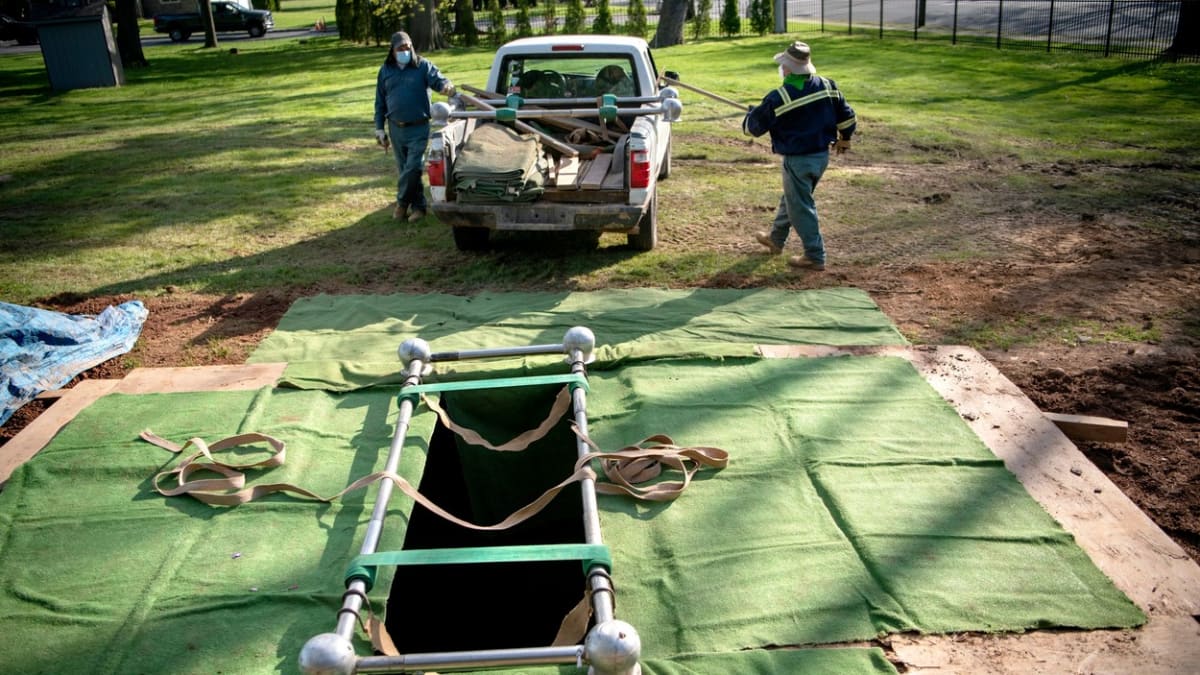 Pracovníci pohřební služby připravují hrob v americkém Cliftonu během pandemie koronaviru.
