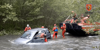 V rozvodněné řece uvázlo auto: Řidič se dostal na břeh, ženu zachránili hasiči