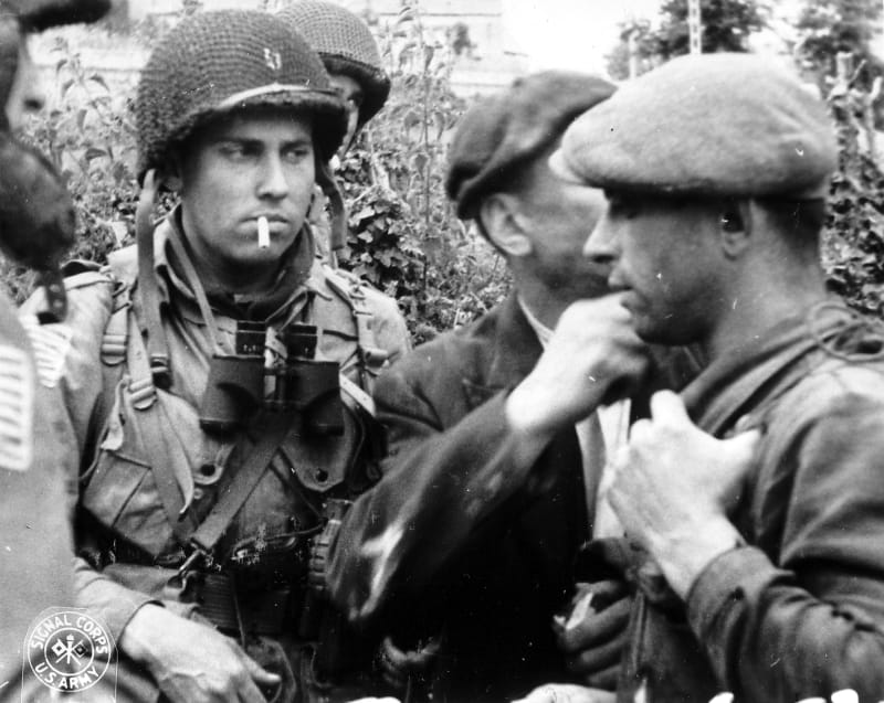 Příslušníci americké 82. výsadkové divize probírají během bitvy o Normandii situaci s příslušníky francouzského hnutí odporu