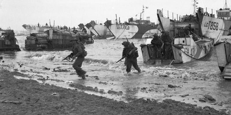 Britští Commandos se 6. června 1944 vyloďují na pláži Gold. velké vyloďovací lodě v pozadí přivezly nákladní auta a další techniku pro 231. brigádu 53. divize