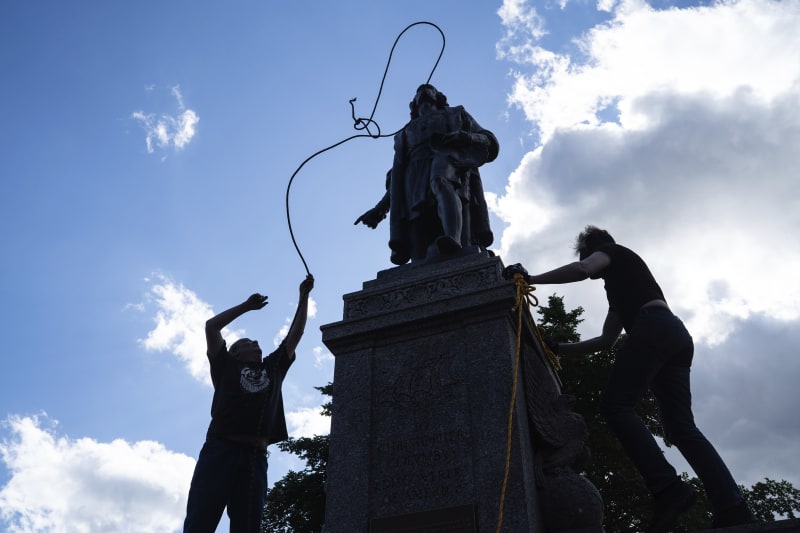 Mike Forcia (vlevo) a další muž se snaží hodit lano na krk sochy Kryštofa Kolumba v americkém městě St. Paul. Nakonec se jim to podařilo a dav sochu svrhl.