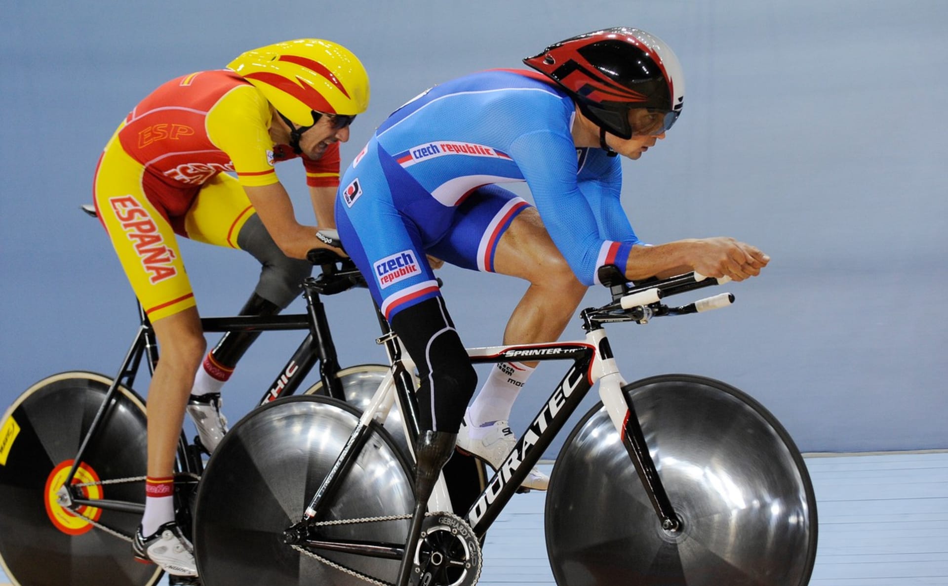 Český reprezentant Jiří Ježek (vpředu v modrém) v souboji se Španělem Robertem Alcaidem při závodě v dráhové cyklistice na paralympijských hrách 2012 v Londýně