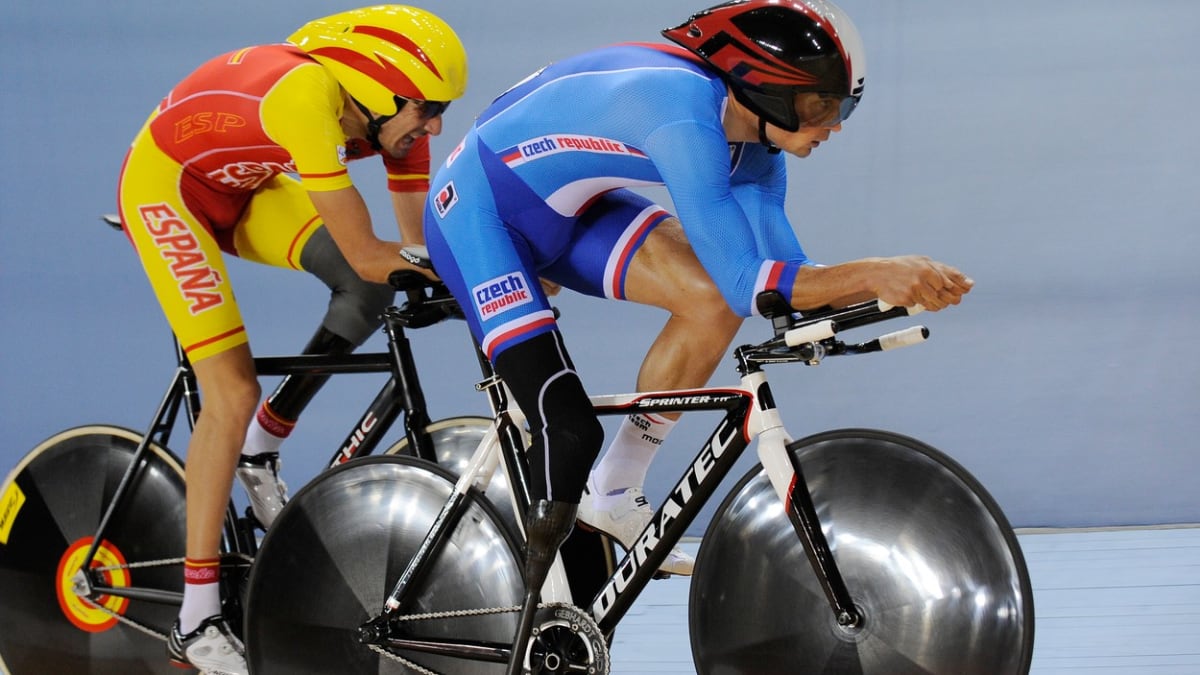 Český reprezentant Jiří Ježek (vpředu v modrém) v souboji se Španělem Robertem Alcaidem při závodě v dráhové cyklistice na paralympijských hrách 2012 v Londýně