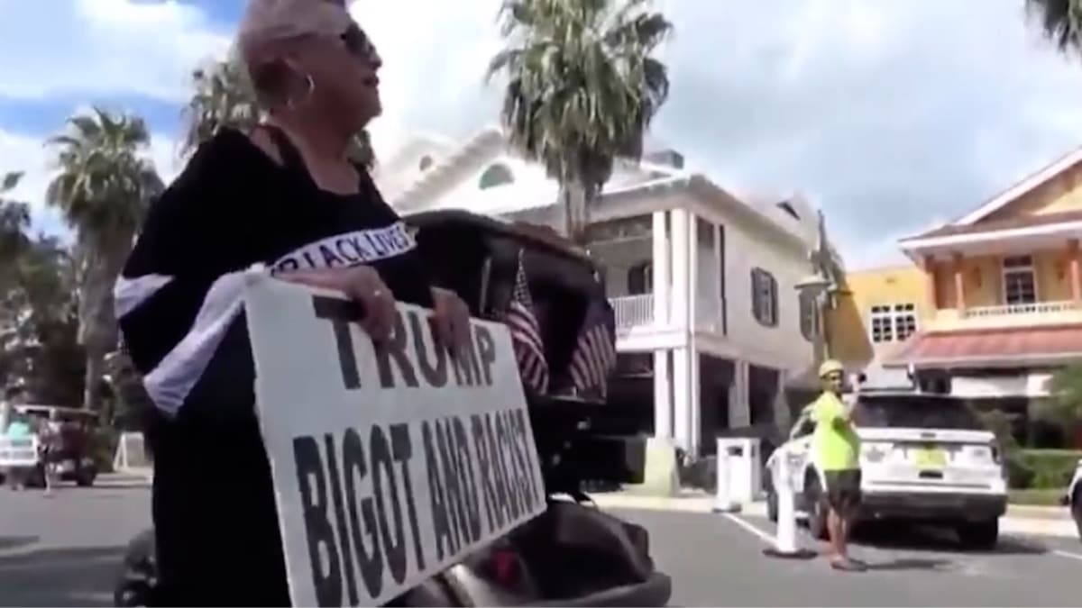 Lidé protestují s podomácku vyrobenými transparenty při příjezdu amerického prezidenta Donalda Trumpa k floridskému Trump National Golf Clubu, kde došlo k incidentu.