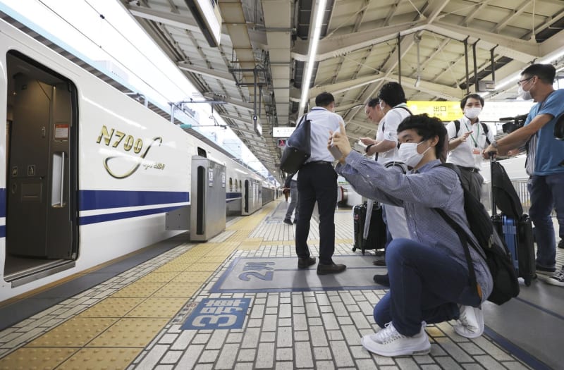 Lidé si fotí nový šinkansen, který právě zastavil ve stanici při premiérové komerční jízdě.