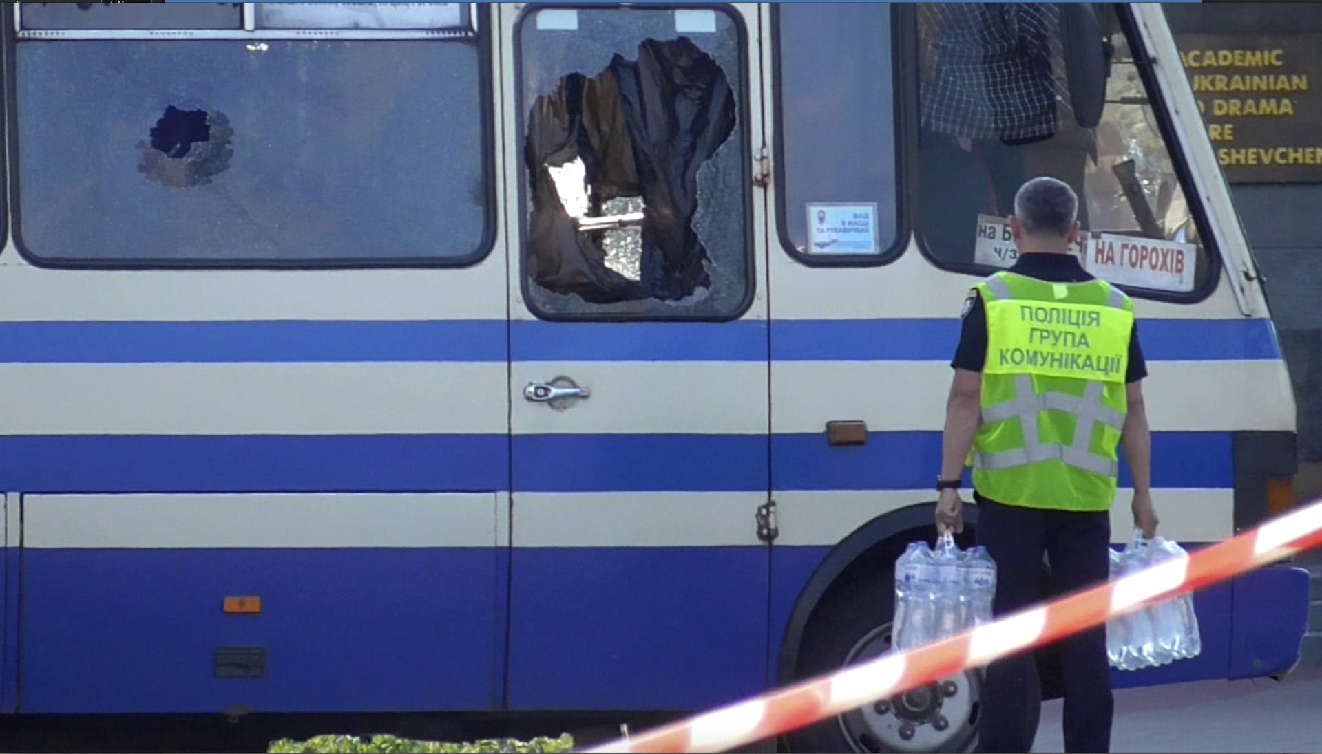 Policista přináší vodu k autobusu, do kterého vnikl v úterý v ukrajinském Lucku Maxim Krivoš a držel v něm devět hodin rukojmí.