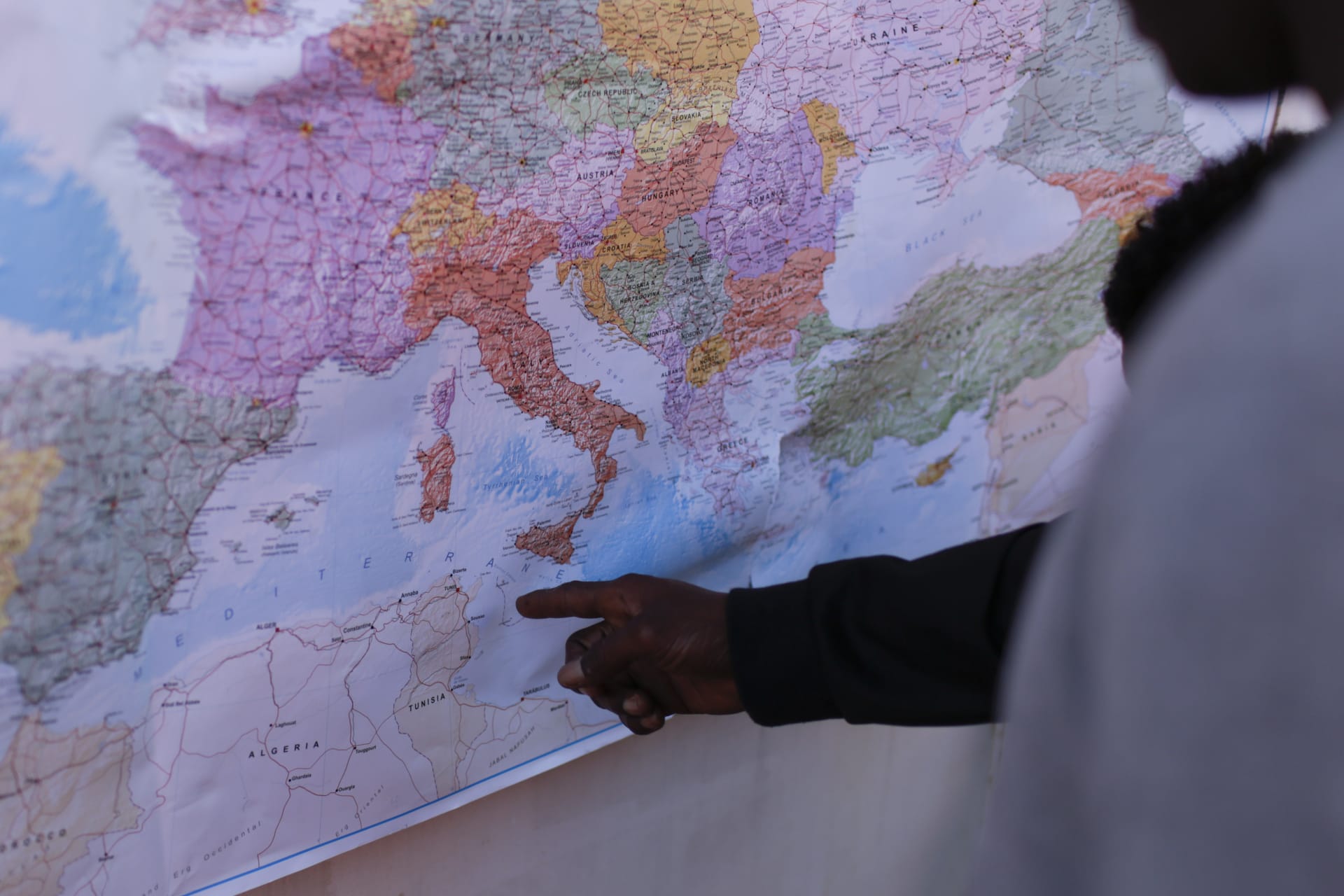 Černošský migrant ukazuje prstem na mapu, kam vedla jeho cesta na lodi Ocen Viking. Na italský ostrov Lamdepusa.