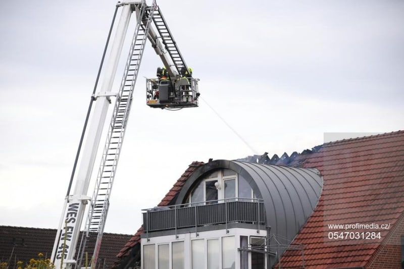 Hasiči dohašují z vysokozdvižné plošiny požár domu v německém městě Wesel, na kterou spadlo malé ultralehké letadlo.