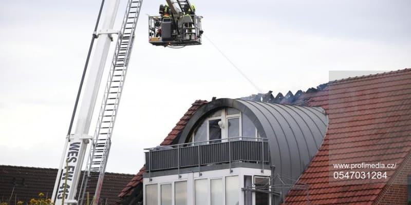 Hasiči dohašují z vysokozdvižné plošiny požár domu v německém městě Wesel, na kterou spadlo malé ultralehké letadlo.