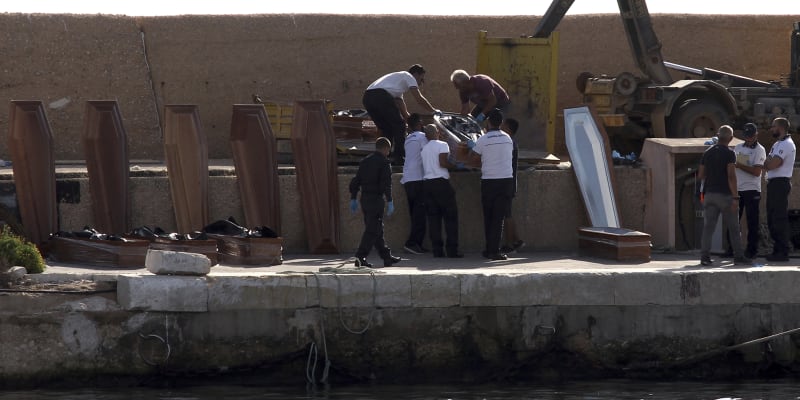 Pracovníci pohřební služby na italském ostrově Lampedusa manipulují s rakvemi, do kterých v přístavu ukládají těla mrtvých migrantů.