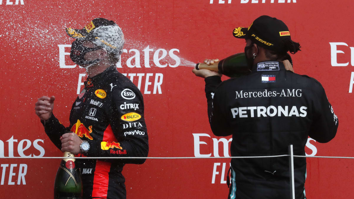 Britský jezdec stáje Mercedes Lewis Hamilton (vpravo) kropí šampaňským vítěze nedělní Velké ceny Formule 1 v Silverstone Maxe Verstappena z Red Bullu. 