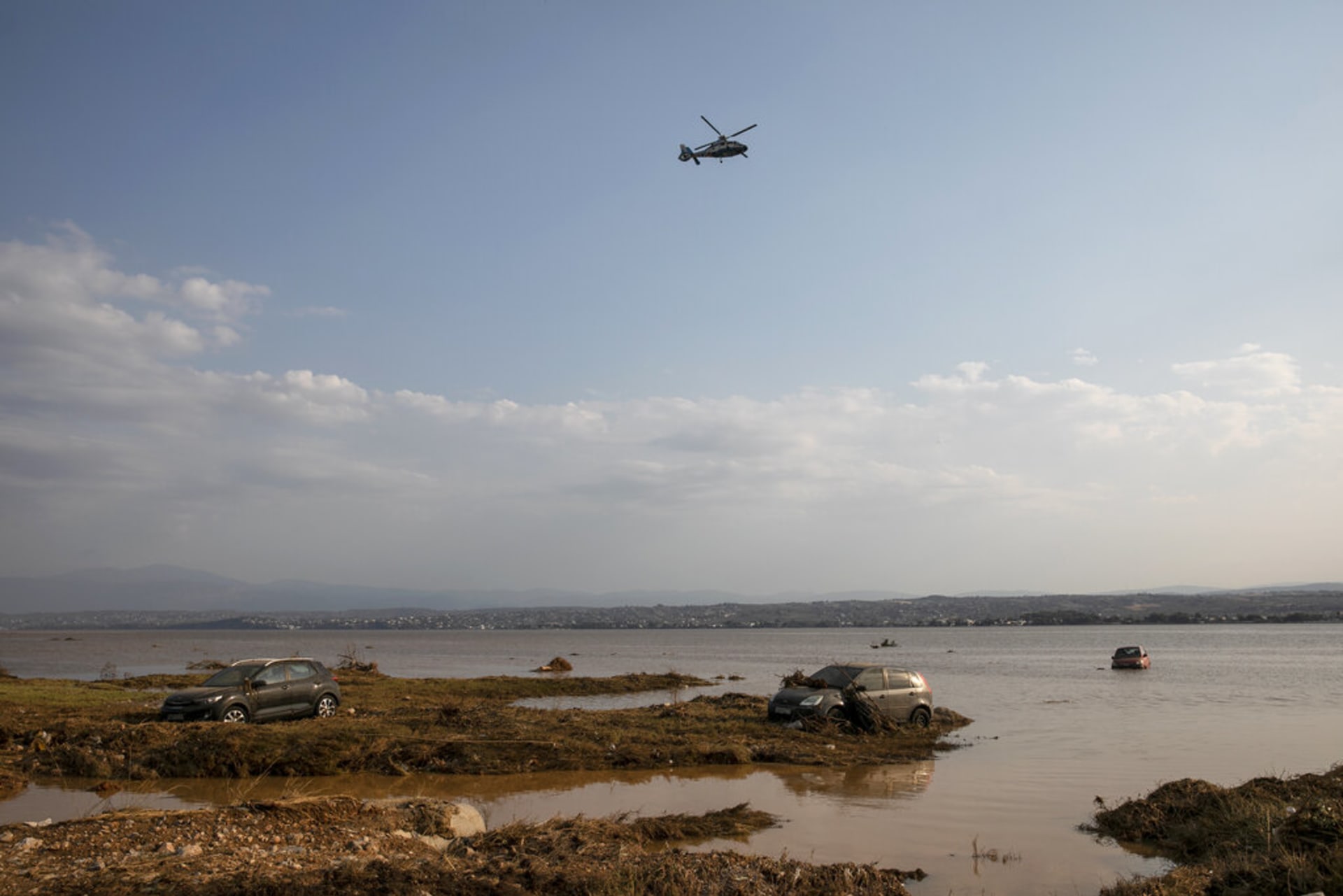 Helikoptéra letí nad vodou odříznutými automobily v obci Bourtzi na ostrově Evia. 