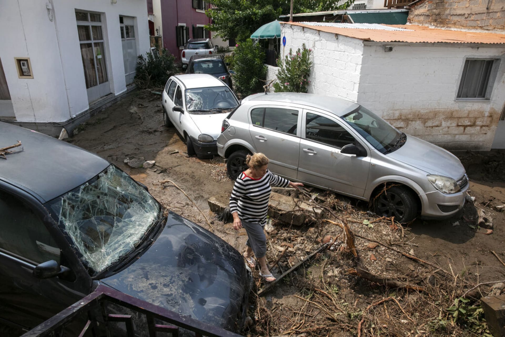 Žena prochází kolem poškozených aut v obci Politika na ostrově Evia. 