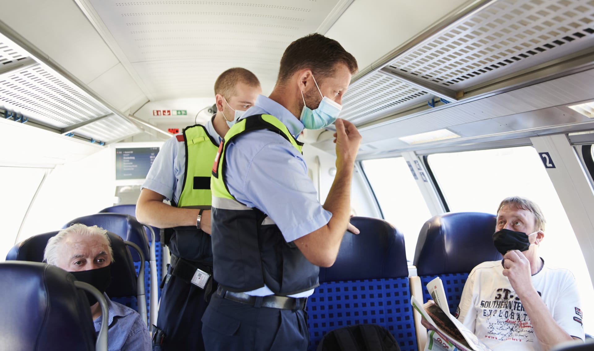 Německý policista a člen bezpečnostní služby Deutsche Bahn kontrolují ve vlaku v Berlíně povinnost nosit roušky.