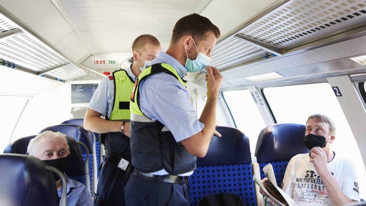 Německý policista a člen bezpečnostní služby Deutsche Bahn kontrolují ve vlaku v Berlíně povinnost nosit roušky.