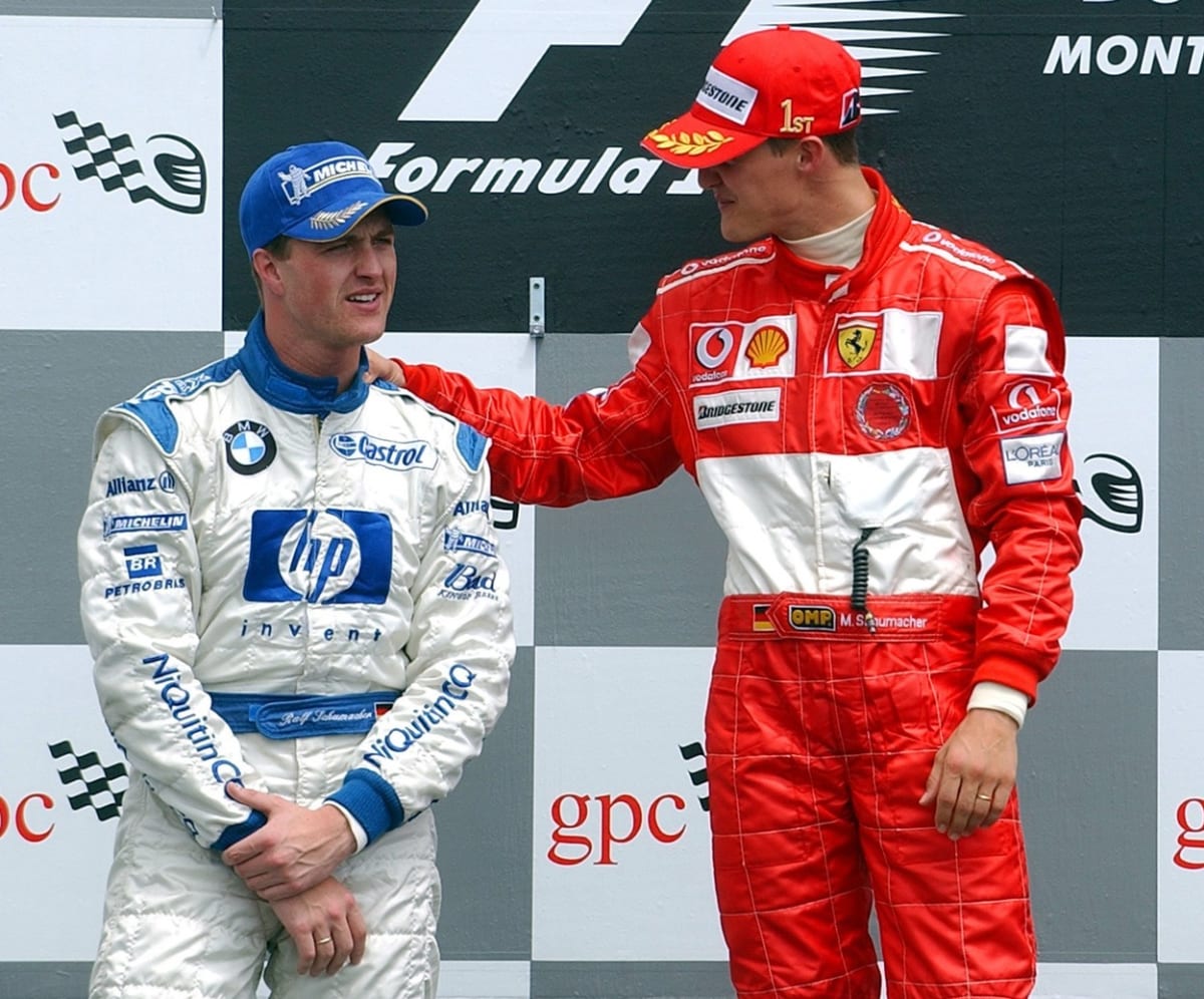 Michael Schumacher uklidňuje na stupních vítězů Ralf Schumachera (vlevo).