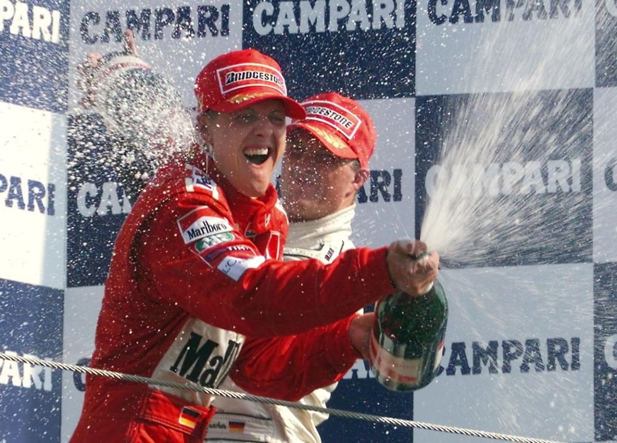 Sprcha šampaňským. Třetí ve Velké ceně Itálie v Monze 10. září 2000 Ralf Schumacher (vzadu) sprchuje šampaňským svého vítězného bratra Michaela.