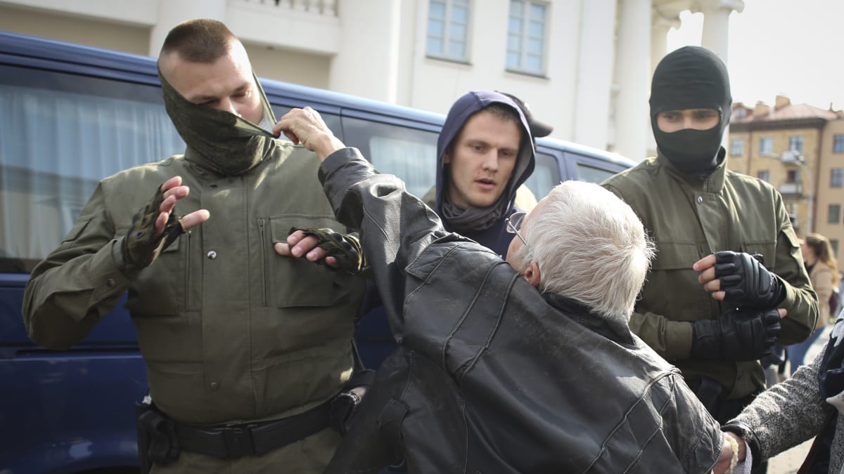 Jedna z demonstrantek se snaží stáhnout masku běloruskému policistovi