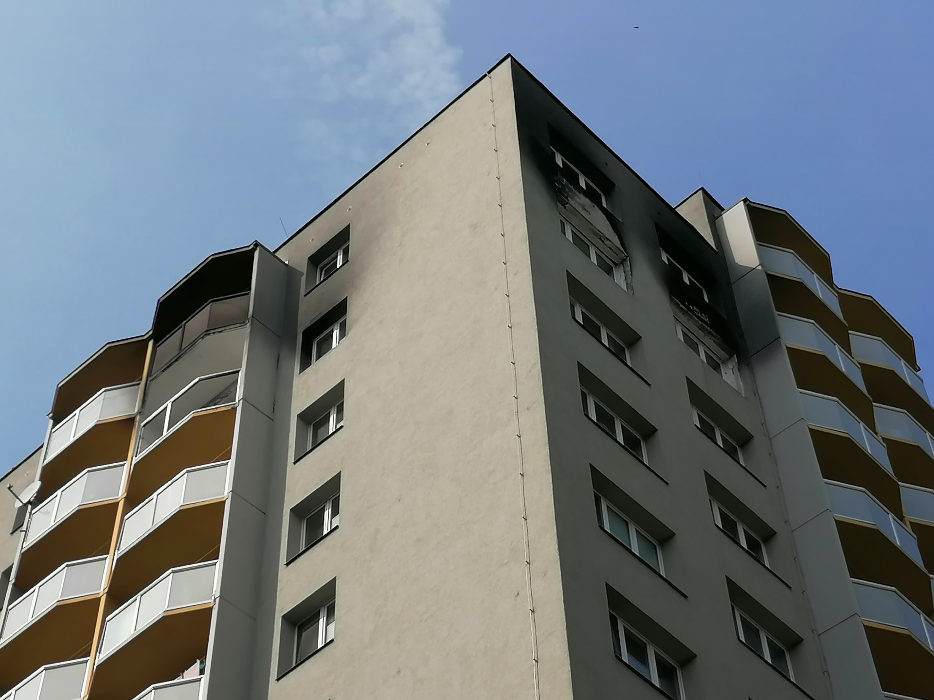 Vyhořelý byt v jedenáctém patře věžáku je téměř opraven, zvenku zůstávají stopy na fasádě