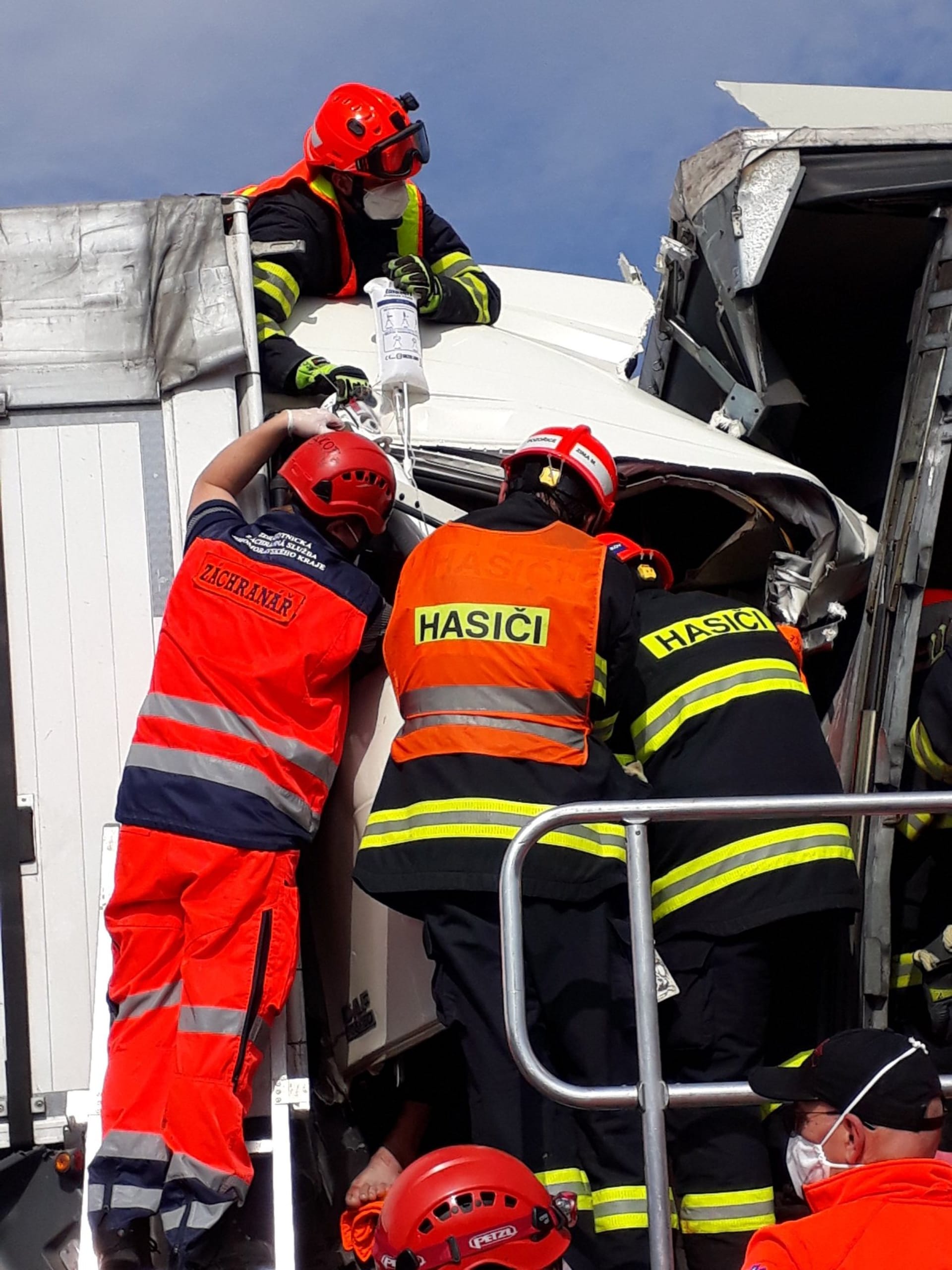 Hasiči a záchranáři se snaží poskytnout pomoc jednomu z řidičů kamionů, který po nehodě zůstal zaklíněný v kabině.