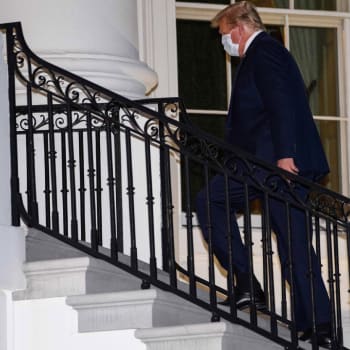 Trump jde po schodech Bílého domu po návratu z nemocnice.