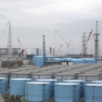 Skladovací nádrže na kontaminovanou vodu v průhledu skrz okno budovy jaderné elektrárny Fukušima v prefektuře Fukušima na severovýchodě Japonska (zdroj: AP)