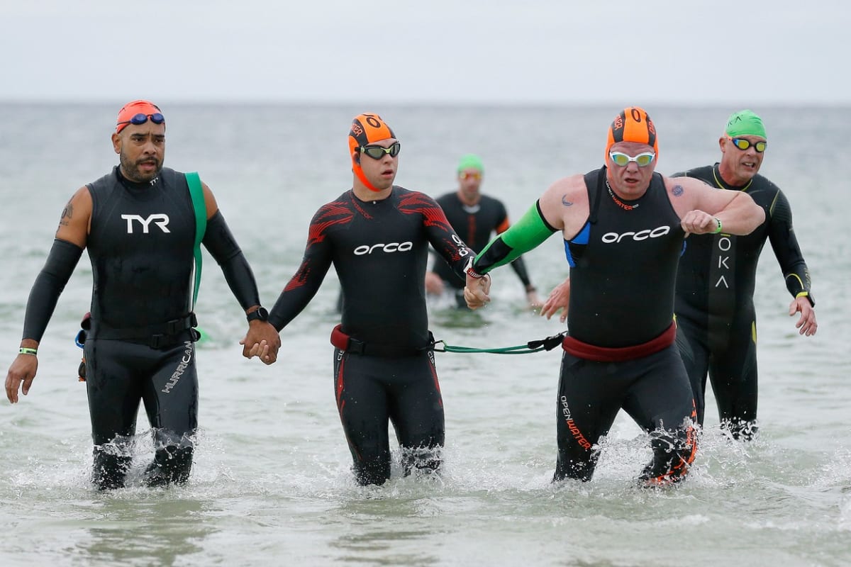 Chris Nikic (uprostřed) a jeho pomocník Daniel Grieb (vpravo) po plavání při Ironmanu na Floridě.