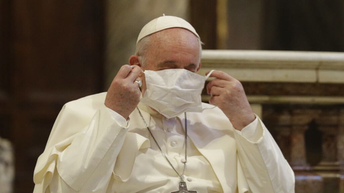 Papež František si nasazuje roušku při kázání v Římě.