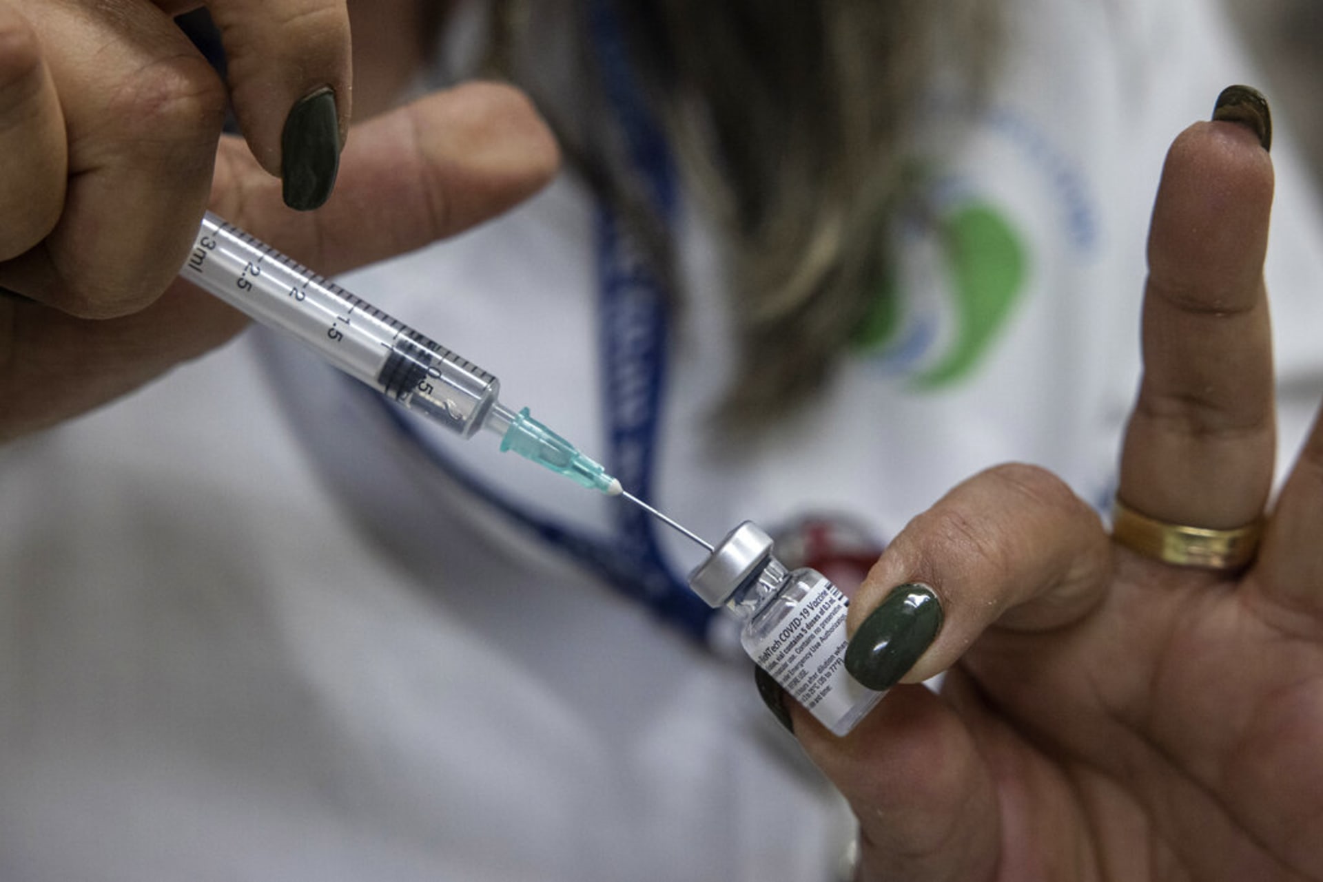 Zdravotnický pracovník napouští do injekce vakcínu proti COVID-19. (Ilustrační foto)