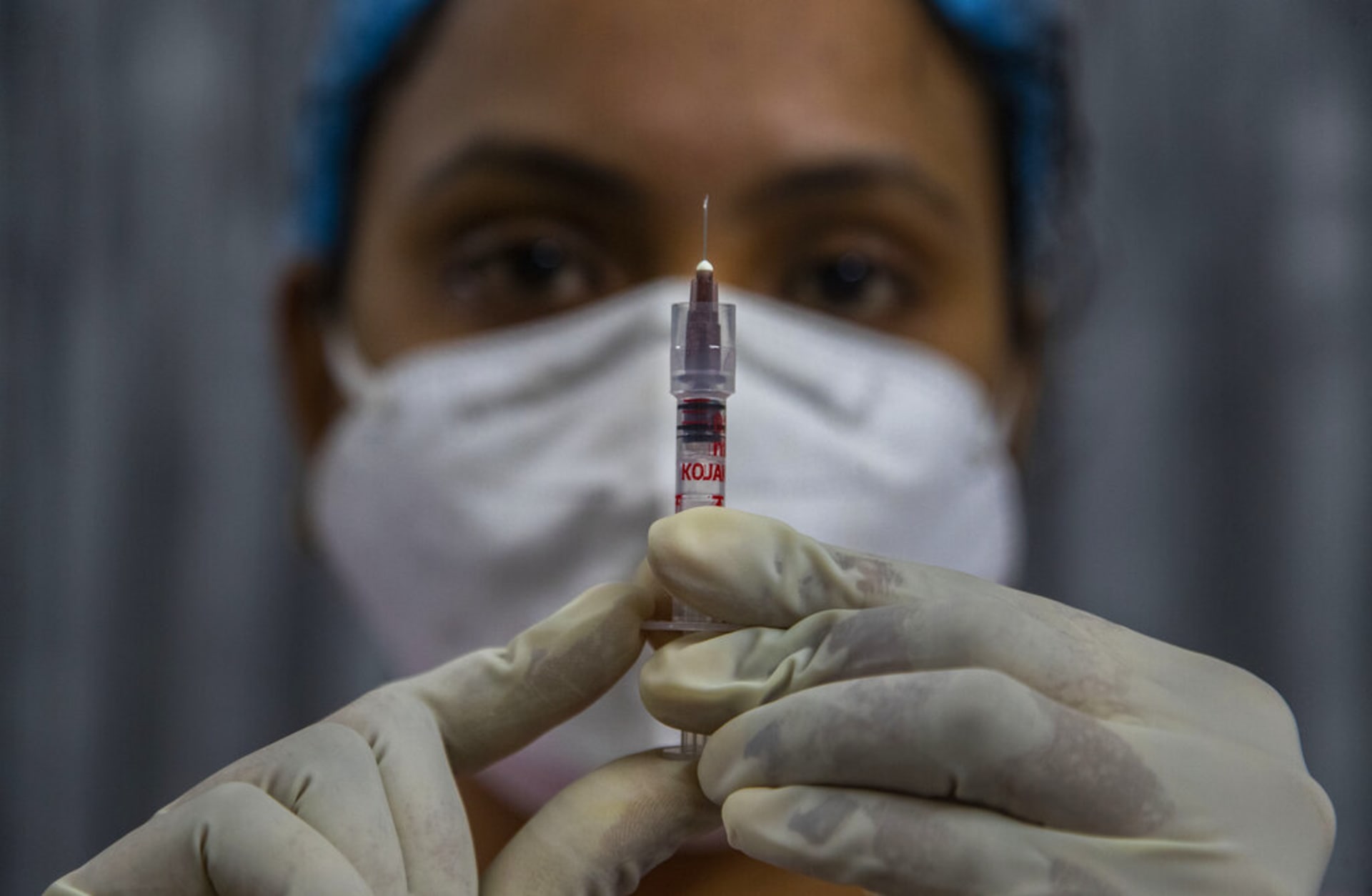 Zdravotník v Indii kontroluje injekci s vakcínou proti COVID-19