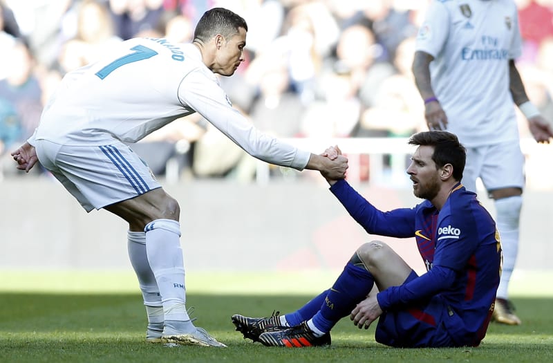 Cristiano Ronaldo (vlevo) pomáhá vstát Lionelu Messimu při zápase španělské ligy FC Barcelona – Real Madrid. 
