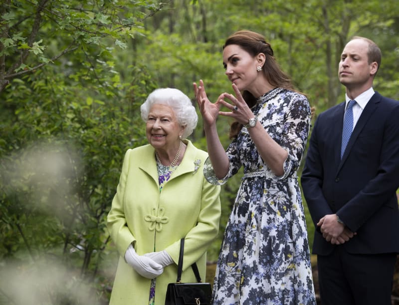 Královna Alžběta II. poslouchá výklad princezny Kate pod dohledem jejího manžela prince Williama při výstavě Zpět do přírody v londýnské Královské nemocnici v Londýně 20. května 2019.