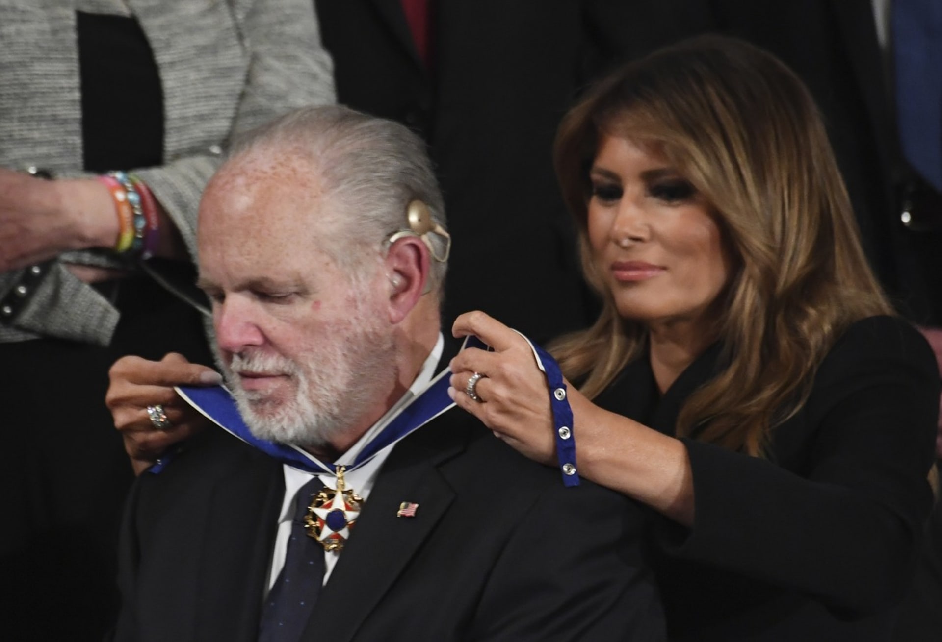 Manželka prezidenta Trumpa Melania dává Limbaughovi na krk prezidentskou medaili svobody, nejvyšší civilní ocenění v USA.
