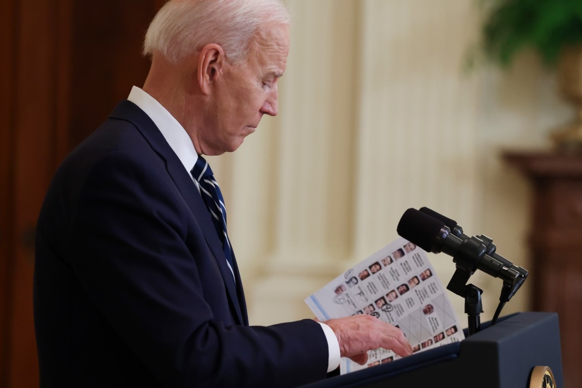 Americký prezident Joe Biden si prohlíží tahák se jmény novinářů.