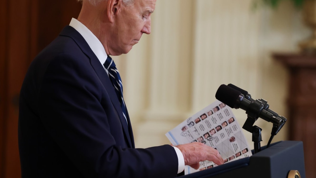 Americký prezident Joe Biden si prohlíží tahák se jmény novinářů.