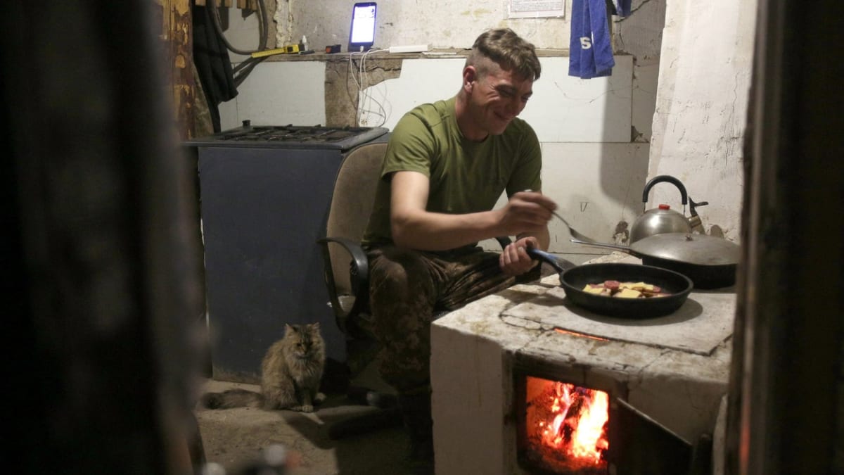 Ukrajinský voják si na frontové linii připravuje jídlo.