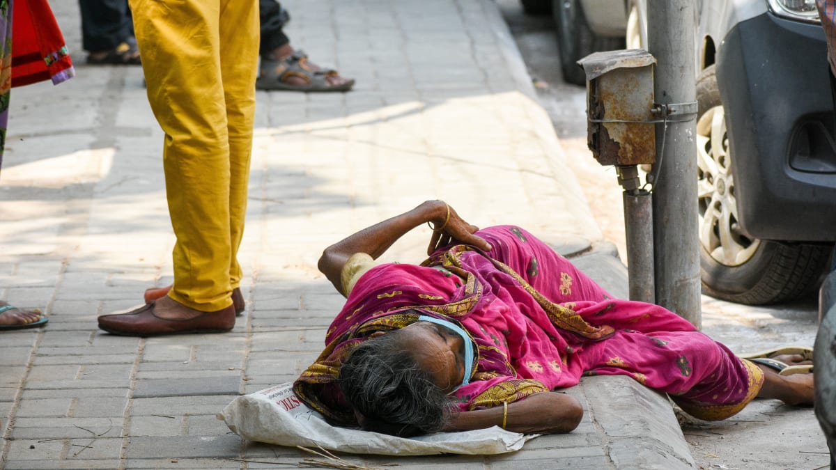Starší žena leží před nemocnicí v indické Kalkatě. 