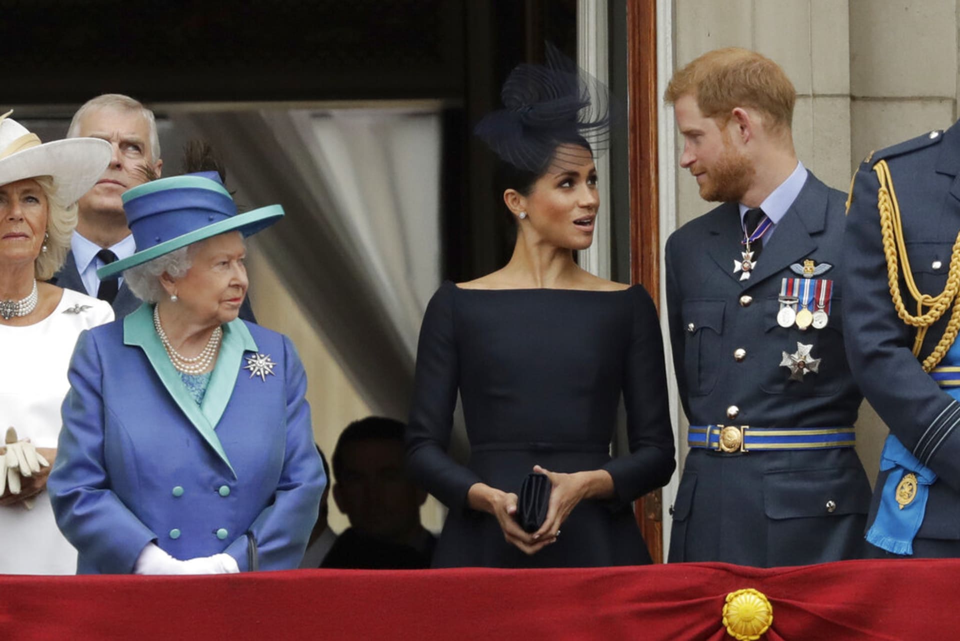Královna Alžběta II., Meghan a Harry v roce 2018, kdy z balkonu pozorovali přelet královského letectva nad Buckinghamským palácem v Londýně.