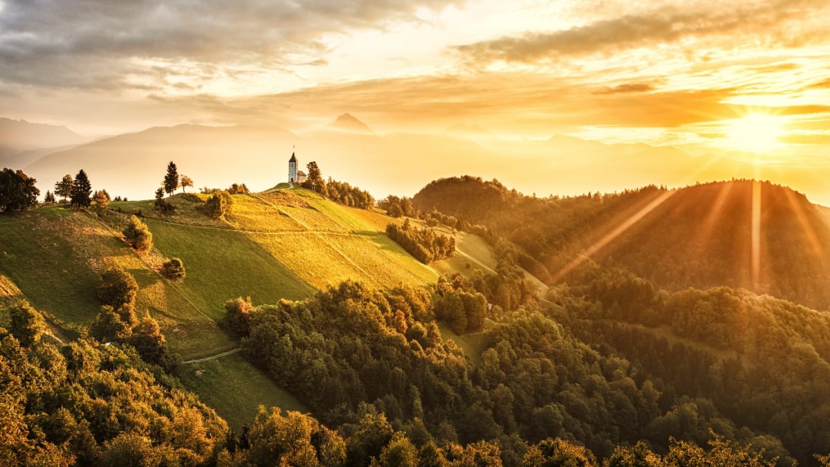 Známý slovinský kostelík na kopcích ve svitu vycházejícího slunce přitahuje mnohé fotografy
