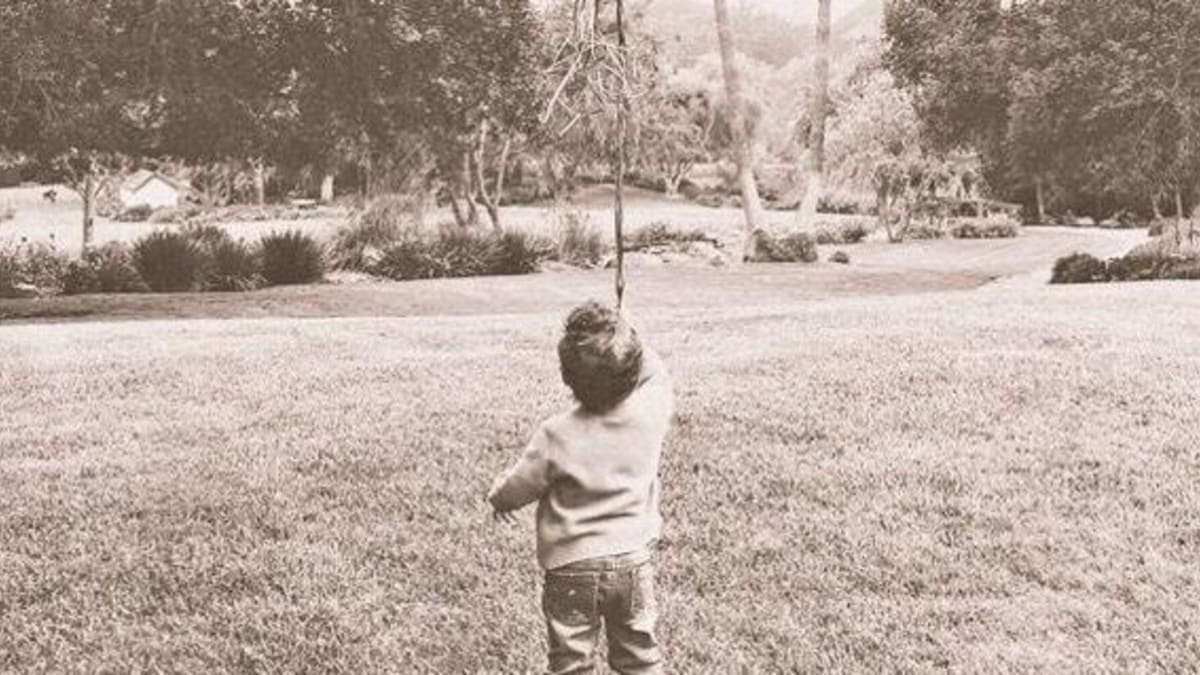 Na fotografii malý Archie drží balónky a je zády k objektivu.