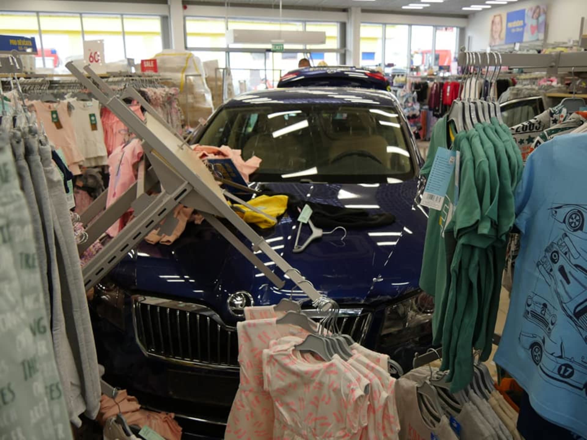 Auto projelo výlohou do obchodu s oblečením.