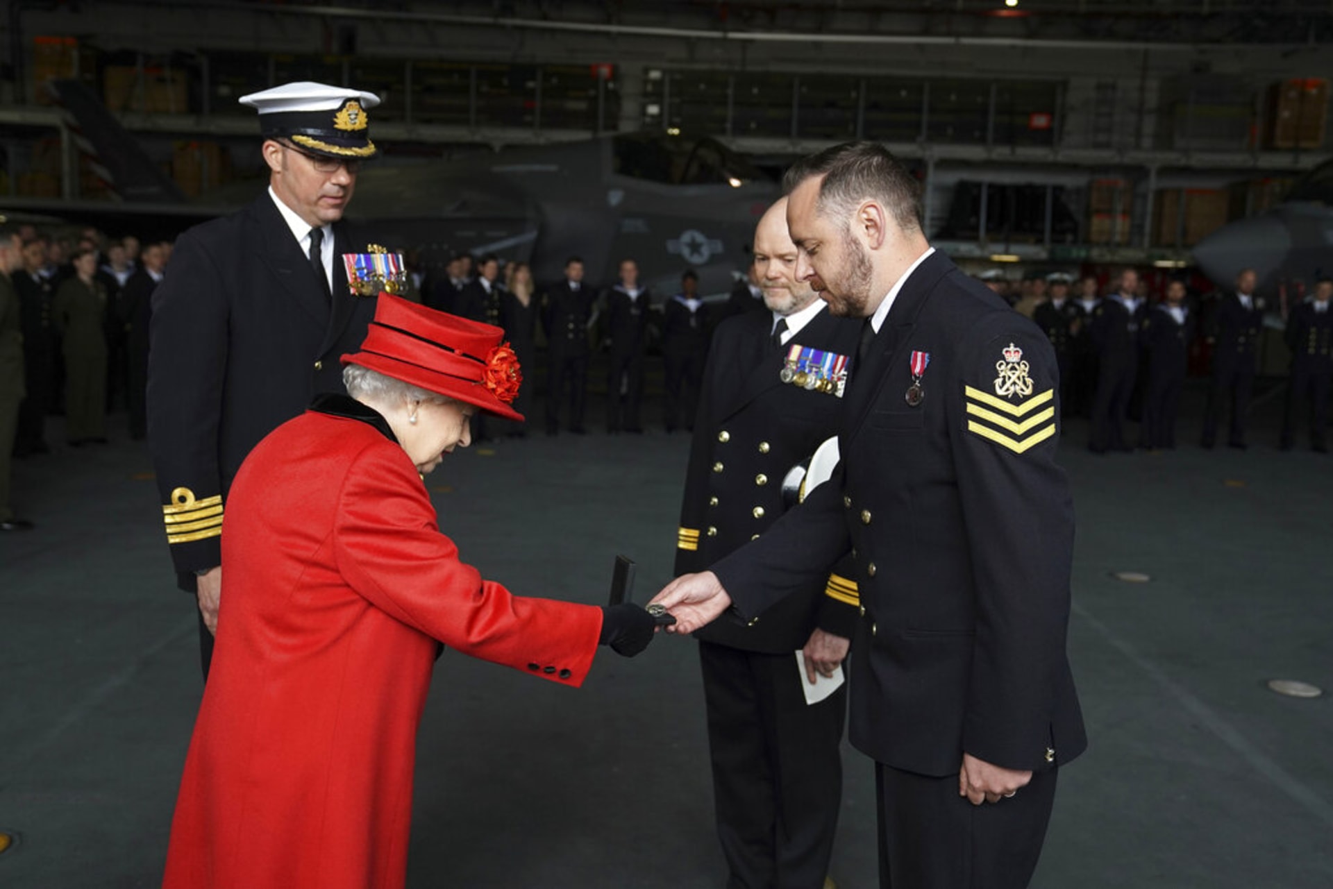Královna Alžběta II. předává ocenění jednomu z vojáků na námořní základně. 