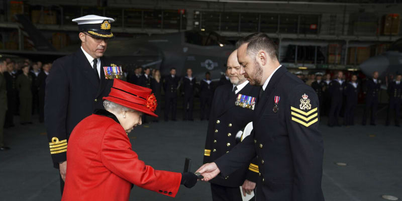 Královna Alžběta II. předává ocenění jednomu z vojáků na námořní základně. 