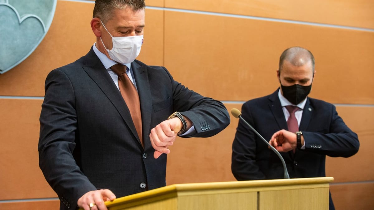 Slovenský ministr vnitra Roman Mikulec (vlevo) se dívá na hodinky během tiskové konference.