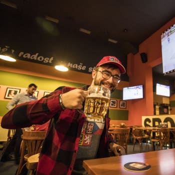 Host v hospodě leduje hokej s pivem v ruce